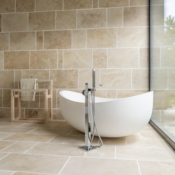 White asymmetric bath and wooden rack for towels in the photo of bright bathroom